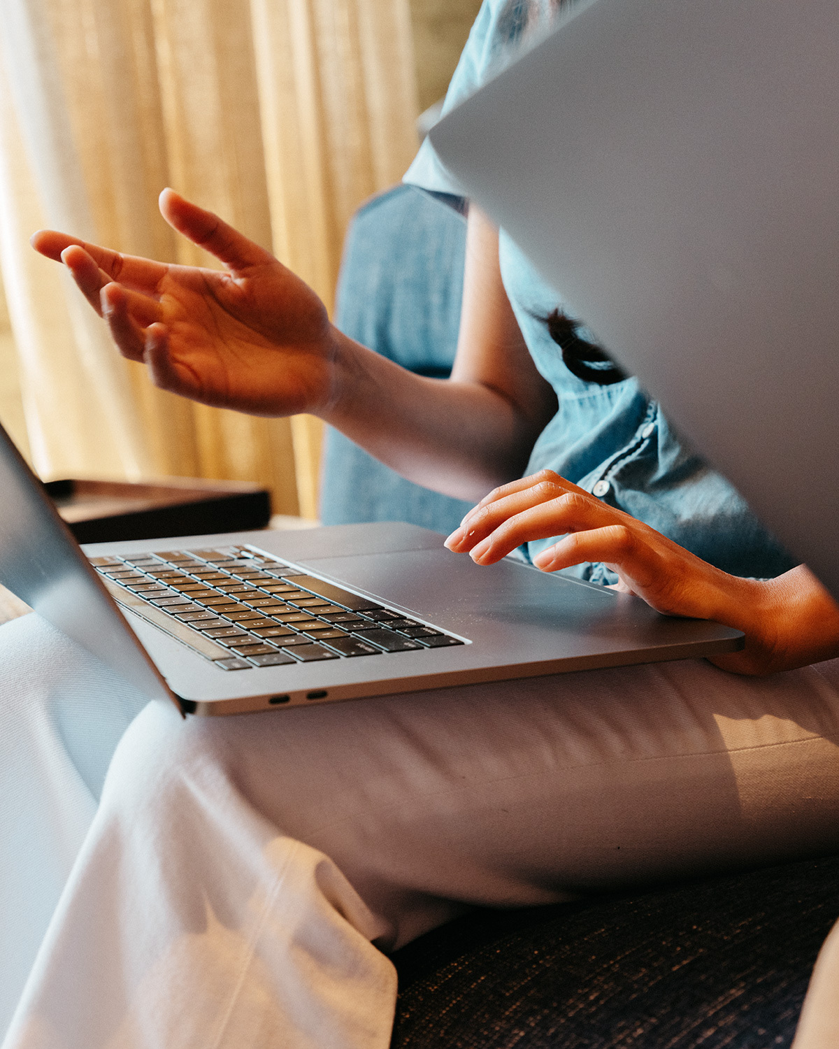 Person using a laptop while discussing work with a colleague